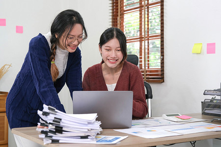 投资市场摄影照片_两名年轻的亚洲女性与新的创业项目创意演示讨论，在家里的笔记本电脑上分析规划和财务统计以及投资市场。