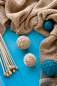 木针位于蓝色背景上明亮的线团和针织毯旁边