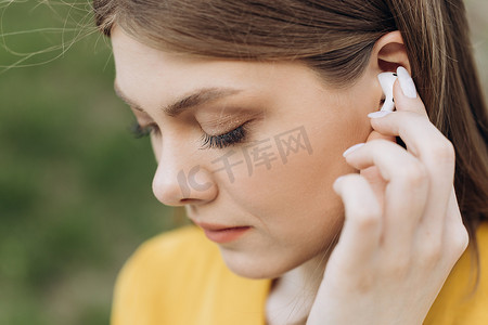 年轻漂亮的女人，耳朵上戴着无线耳机。