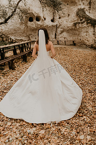 穿着婚纱的新娘穿过秋天的森林，在落下的橙叶上跑到山上