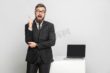 男人站在他的工作地点附近，张开嘴伸出手指。