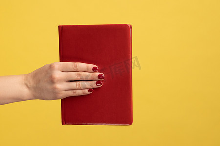 女人手拿红书，情节有趣，愉快地学习。