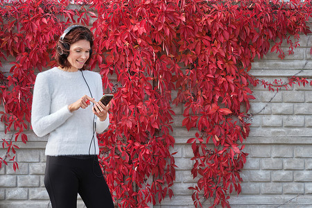 搜索秋天摄影照片_白人女性在户外用手机听音乐