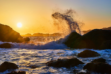 日落时海浪从大岩石上溅起的惊人飞溅