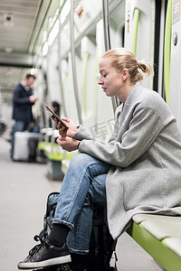 可爱的女孩在几乎空荡荡的公共地铁列车上用手机打字的肖像。