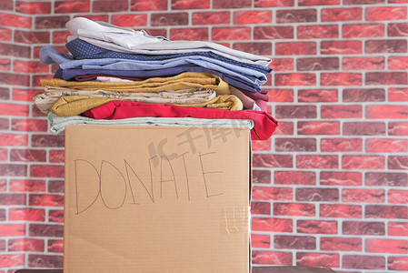 捐款箱摄影照片_木桌上有捐赠衣服的捐款箱。