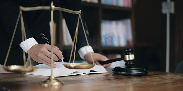 双边平衡车摄影照片_正义和法律概念。法庭上的男法官在木桌上，辅导员或男律师在办公室工作。