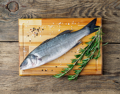 新鲜的、生的、咸水鱼、鲈鱼在旧木板上的木切板上，质朴的桌子，顶视图