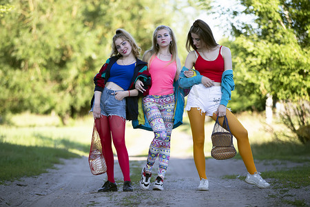 三个穿着九十年代风格的漂亮乡村姑娘沿着路走。