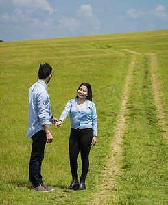 美丽的情侣在田野里牵着手互相看着对方，两个恋人在田野里牵着手，两个人在田野里牵着手