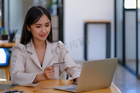 网上购物和互联网支付，美丽的亚洲女性正在使用信用卡和笔记本电脑在网上购物或在数字世界中办事