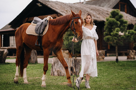 庄园牧场摄影照片_老牧场上一匹马旁边穿着白色太阳裙的漂亮女孩