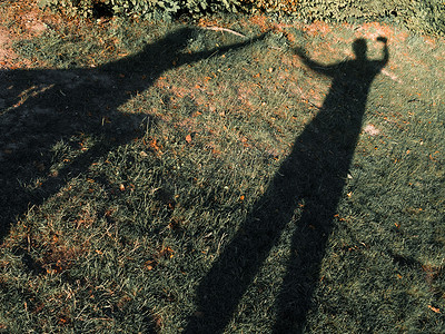 绿色剪影人物摄影照片_草地上的情侣影子