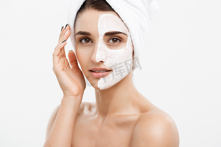 药健康摄影照片_美容护肤概念-美丽的白种女人脸部肖像在她的面部皮肤白色背景上应用奶油面膜。