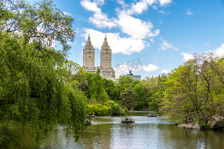古埃尔公园长椅摄影照片_美国纽约 — 2019年5月15日：美国纽约市曼哈顿中央公园湖中划船，远处是埃尔多拉多建筑
