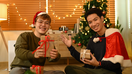两个快乐的人拿着圣诞礼物，对着镜头微笑。