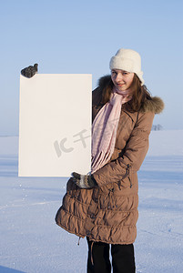 亲子郊游海报摄影照片_冬天雪地拿着白色海报的女孩