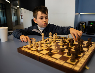 可爱聪明的小学男孩思考棋步，在下棋时制定策略。