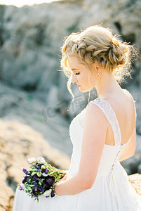 新娘手捧鲜花摄影照片_新娘穿着白色礼服，手捧鲜花。