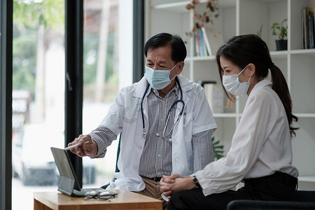 资深亚洲医生咨询年轻女性患者，在体检时与客户交谈。