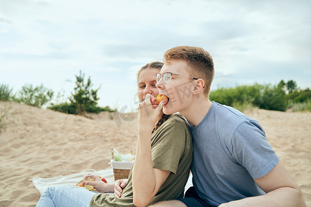 互相喂食摄影照片_年轻夫妇在海滩上互相喂食的爱情故事