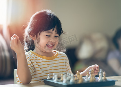 亚洲小婴儿在家里的客厅里下棋。聪明的孩子。时尚的孩子。