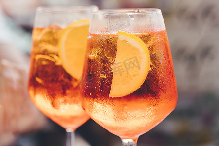 一杯冰镇阿佩罗雪碧鸡尾酒装在酒杯中，装饰着橙片。