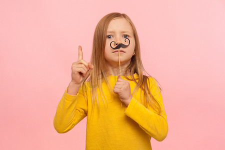 专横的姜黄色小女孩，留着滑稽的纸胡子，做出更好的手势，提供建议