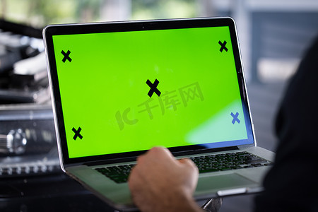 it软件摄影照片_汽车服务机械师使用带有绿屏模拟色度键汽车诊断软件的笔记本电脑。