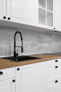 黑色现代简约摄影照片_简约而优雅的厨房，配有木质台面、白色橱柜、抽屉和黑色水槽。