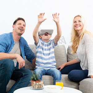 幸福的家庭在客厅沙发上享受使用虚拟现实耳机玩游戏的乐趣