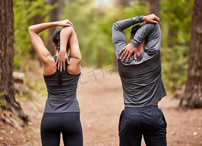 年轻男女运动员在大自然中跑步前伸展身体的后视图。