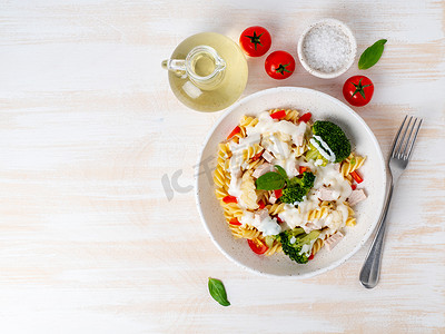 意大利面螺丝，配蔬菜、肉、白木桌上的白酱、低热量饮食、低脂食物、顶视图、复制空间