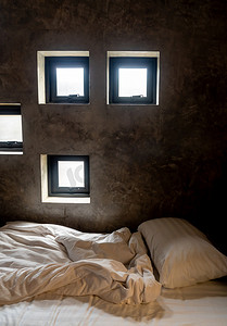 床垫皱巴巴的，深色旧水泥墙上的灯孔发出眩光