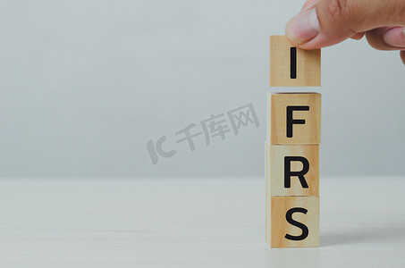 手工将木立方体 IFRS 国际财务报告标准放在桌子和复制空间上。商业财务概念。