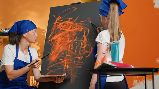 母亲和孩子用画架在画布上使用水彩颜料