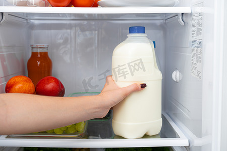 女手从冰箱里拿瓶牛奶