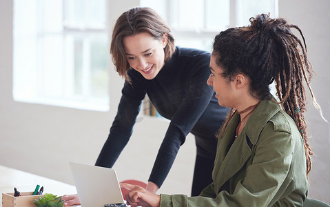两名商界女学生使用笔记本电脑团队领导女性帮助同事分享项目想法