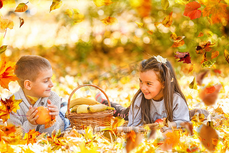 两小孩子摄影照片_在阳光明媚的秋日，两个穿着鲜艳夹克的可爱微笑的小孩子一起在公园里散步。