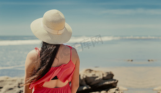 戴帽子的女人从背对大海，戴帽子的女孩望向大海，度假概念，一个女孩看海的后视图