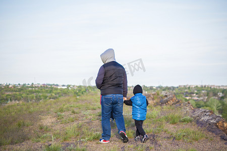 发生的摄影照片_一个男人和孩子们站在一块岩石上，看着下面发生的事情。
