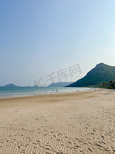 夏天大海沙滩背景摄影照片_热带沙滩，郁郁葱葱的绿色山脉，蓝天和美丽的风景。