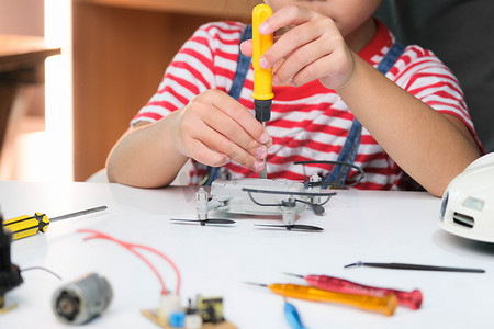 专注的小女孩用手中的工具修理她的玩具无人机，并用螺丝刀仔细组装玩具无人机。