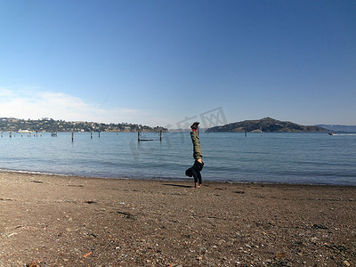 穿着连帽衫、裤子和鞋子的男子在索萨利托的海滩上倒立
