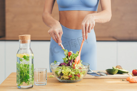 特写照片、身体部位、年轻健身女性在家里厨房用新鲜蔬菜制作沙拉和新鲜排毒饮料的手