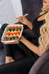 用筷子特写吃寿司、食品外卖和送货服务、鲑鱼寿司卷、美味佳肴、寿司送货。