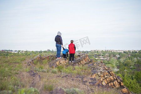 一个男人和孩子们站在一块岩石上，看着下面发生的事情。
