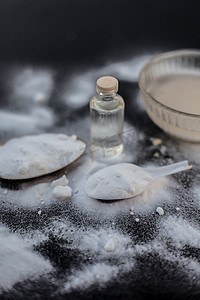 将面膜或小苏打面膜装在木质表面的玻璃碗中，将粉末和一些椰子油装在透明玻璃瓶中。
