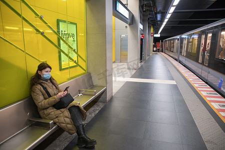 一位身穿温暖羽绒服、配有绿屏智能手机的年轻女子坐在地铁里