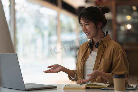 使用笔记本电脑视频聊天应用程序在移动聊天应用程序中与朋友在线进行视频通话的亚洲女性肖像。